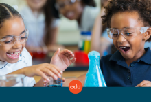 Two children in safety glasses working with beakers.