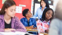 High school teacher speaking with student in classroom