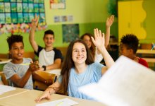 Middle school students raise hands in class
