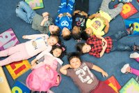 Group of Pre-K kids lying in a circle with their heads touching.