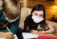 Children doing homework at home in masks during quarantine covid-19