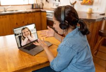 Primary teacher and pupil interacting in live video lesson. Woman tutor with headset and laptop working remotely from home online teaching child student in video conference.