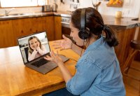 Primary teacher and pupil interacting in live video lesson. Woman tutor with headset and laptop working remotely from home online teaching child student in video conference.