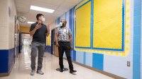 Under the careful watch of principal Keith Moore (r) and a staffer, in-person learning resumes for the first time since March at Campbell Elementary in Austin.