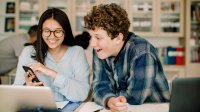 High school students work on computer together in class. 