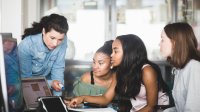 Teacher works in small group with high school students in school