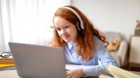 Elementary student at home on laptop with headphones