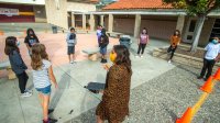 Teacher leads students in a group activity outside the school