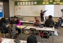 High school math teacher instructs her class in front of a whiteboard