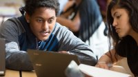 Two high school students collaborate in class using a laptop