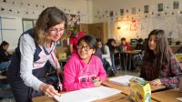 Teacher helps high school student with work in classroom