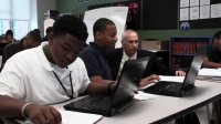 High School students are working on their computers. A teacher is helping them.