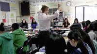 Teacher is teaching a group of senior students in a classroom.