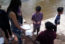 A group of students are working on their works and gather around the river 