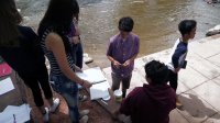 A group of students are working on their works and gather around the river 