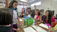 Students are showing their engagement to the teacher by raising up their hands to answer the question in the classroom.