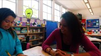 A teacher is helping her student on their assignment in a classroom.