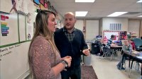 Two teachers are talking in front of the classroom.