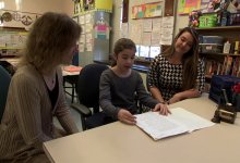 Two teachers are working with a student in a classroom