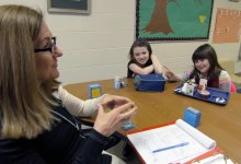 A teacher and students are working together in a working group setting.
