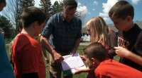 Students and teacher are working together in an outdoor setting.