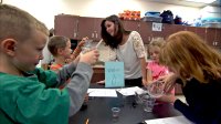 Primary students are working in a science class with their teacher.