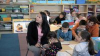 Teacher is teaching a group of primary students in a classroom.