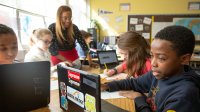 Middle school classroom with teacher and students and laptops