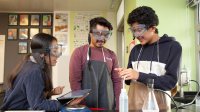 Students in high school science class do an experiment with help from tablet