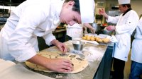 Young man prepares food in restaurant kitchen