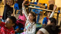 A third grader raises her hand in class