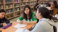 Three high school students work together in their school library