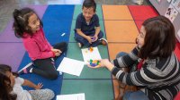 Elementary teacher works on a math assignment with children during circle time