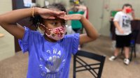 An elementary school student wears a mask during a drama camp activity