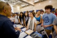 Students and parents listen to a college recruiter at a college fair