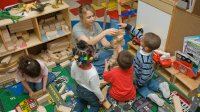 Teacher and pre-k children in classroom play with blocks. 