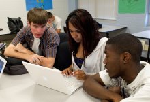 Three high school students work on a laptop together
