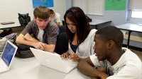 Three high school students work on a laptop together