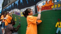 Student paint an outdoor wall mural