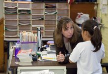 Teacher bending over talking to elementary student