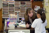 Teacher bending over talking to elementary student