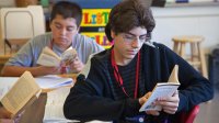 Eighth graders read books in while sitting their desks in class