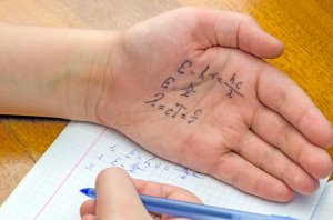 A student cheats using answers on his hand. 