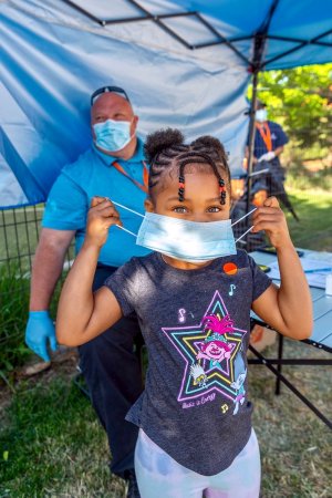 A child puts on a mask at Clayton Early Learning Center in Denver.