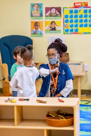 A preschool teacher elbow bumps a student in Denver.