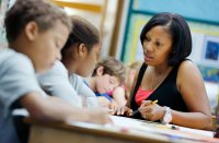 Teacher sitting at student's desk and reviewing an assignment