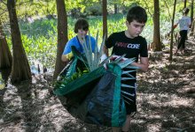 Middle schoolers help clear an area for an outdoor classroom