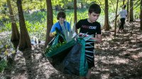 Middle schoolers help clear an area for an outdoor classroom