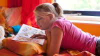 Teenage girl reading a comic book in her bedroom