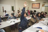 High school students raising their hands in class